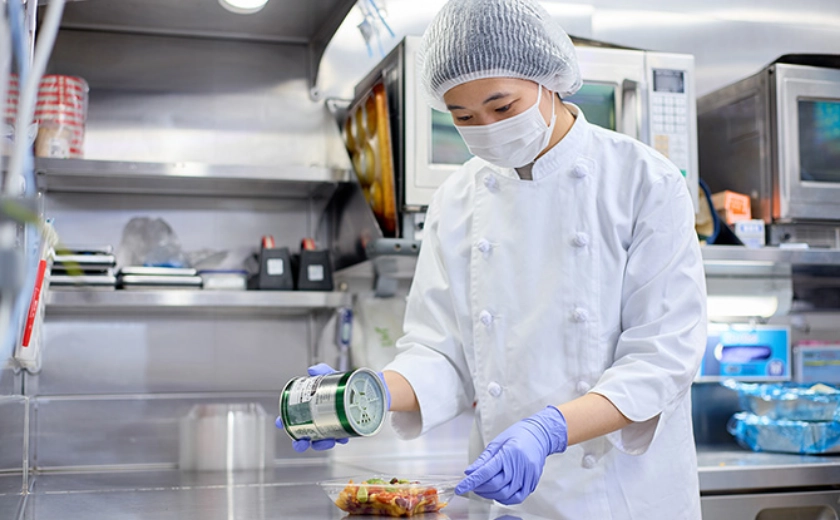 惣菜の盛付をするNさん