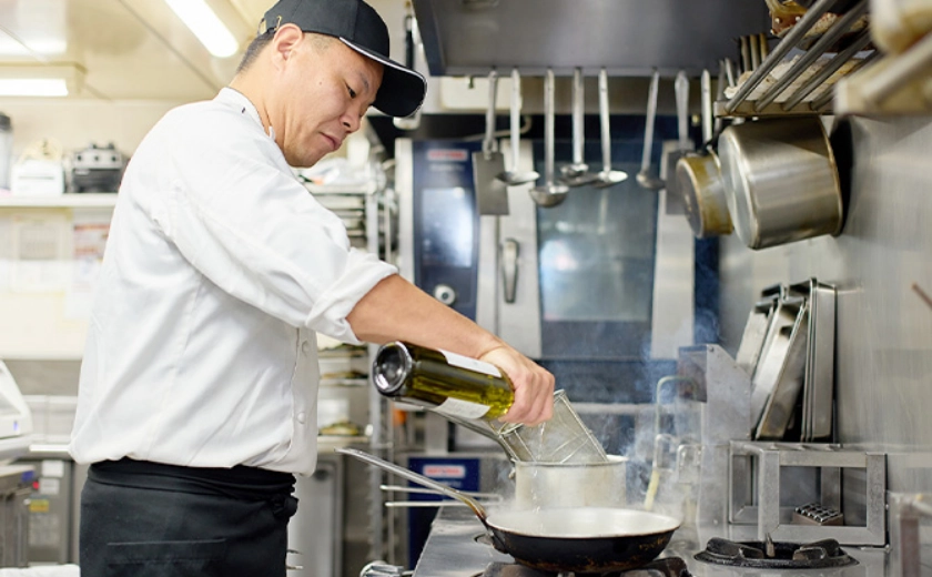 レストランのキッチンで調理するFさん