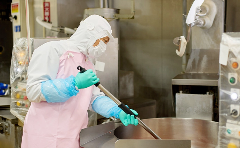 大きな鍋をかき混ぜるKさん